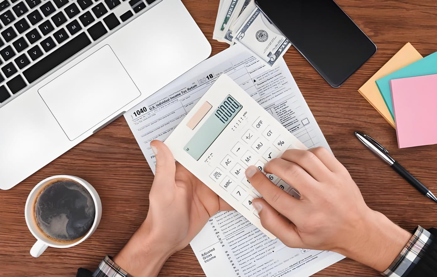 A person using a calculator with shipping documents in the background
