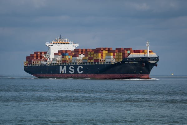 A container ship on the ocean with a focus on dangerous goods placards.