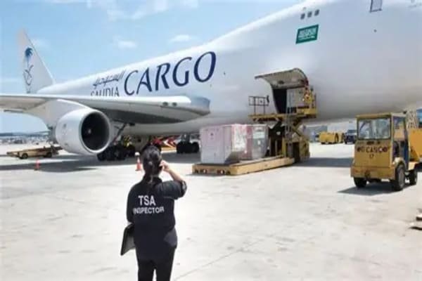 An airport cargo area with security personnel inspecting packages