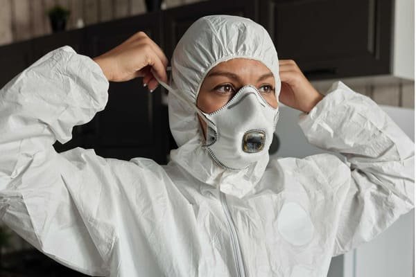 Emergency responders in full hazmat suits cleaning up a chemical spill from a drum