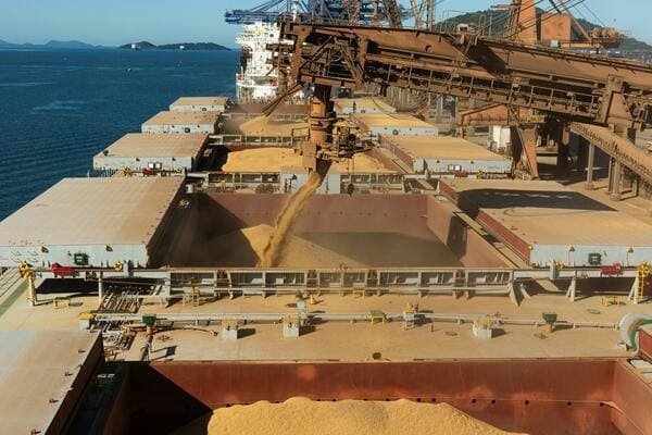 A crane lifting a large piece of industrial machinery onto a ship