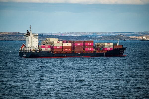 A container ship at a busy port with a soccer ball graphic overlaid
