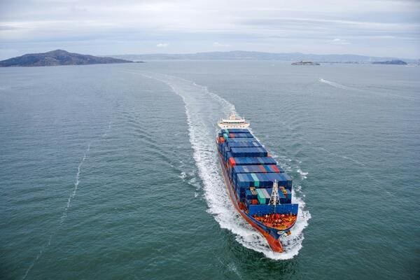 An image showing a container ship and a magnifying glass over a document with HS codes