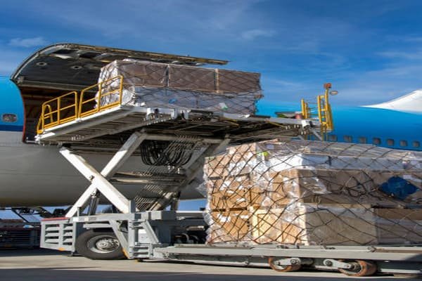 A logistics worker carefully applying a "ShockWatch" indicator to a large shipping crate.
