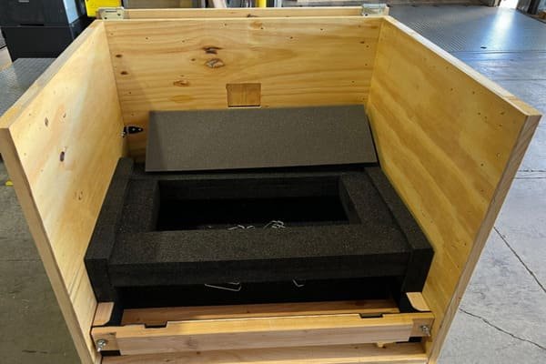 An exploded view of a multi-layer packaging system with an outer crate, foam inserts, and the instrument suspended inside.