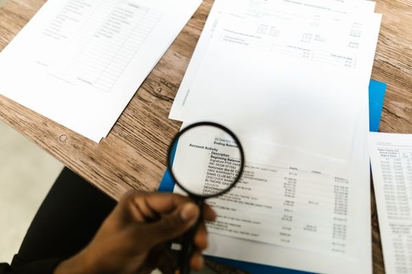 A magnifying glass over a shipping invoice, highlighting hidden costs