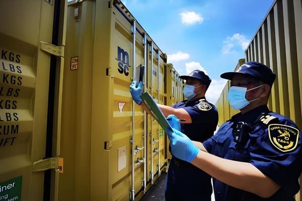 A magnifying glass hovering over a shipping container, symbolizing inspection and due diligence in logistics.